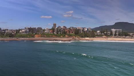 Aerial-over-the-ocean-and-revealing-North-Wollongong-Beach-and-high-rise-buildings-beyond