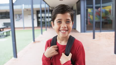 en el patio de una escuela, un joven caucásico sonríe brillantemente