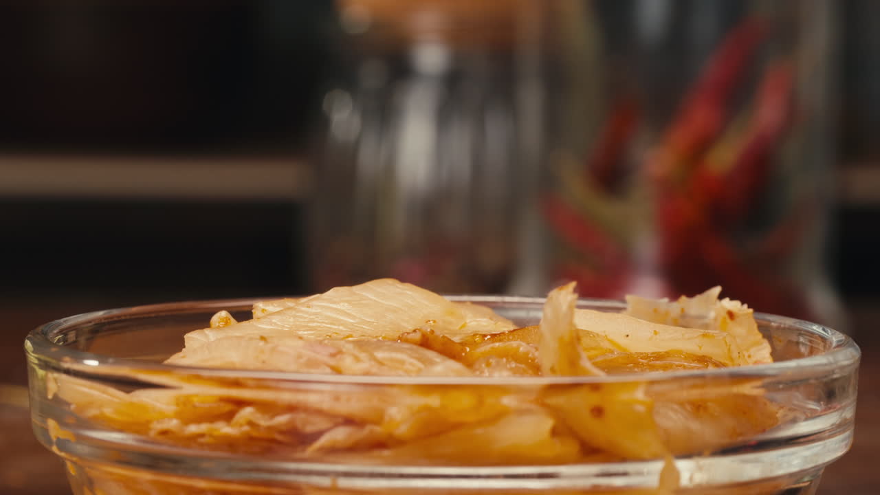 Taking a little bit of fermented spicy cabbage kimchi with chopsticks close-up. Preservation of vegetables in glass jars. Fermentation preserved kimchi cabbage with spices macro. Asian cuisine.