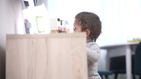 baby playing on the floor with building blocks, then gets up and takes his first steps to the dresser to get another toy