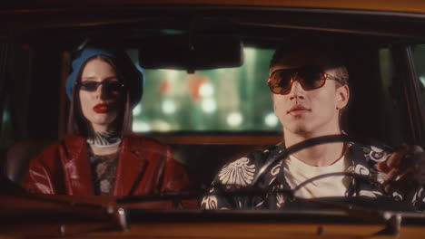 young man talking with female passenger in retro car during night drive