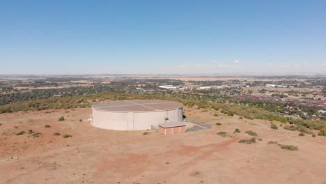 drone shot of water supply tank supplying water to a town in the background on a sunny day