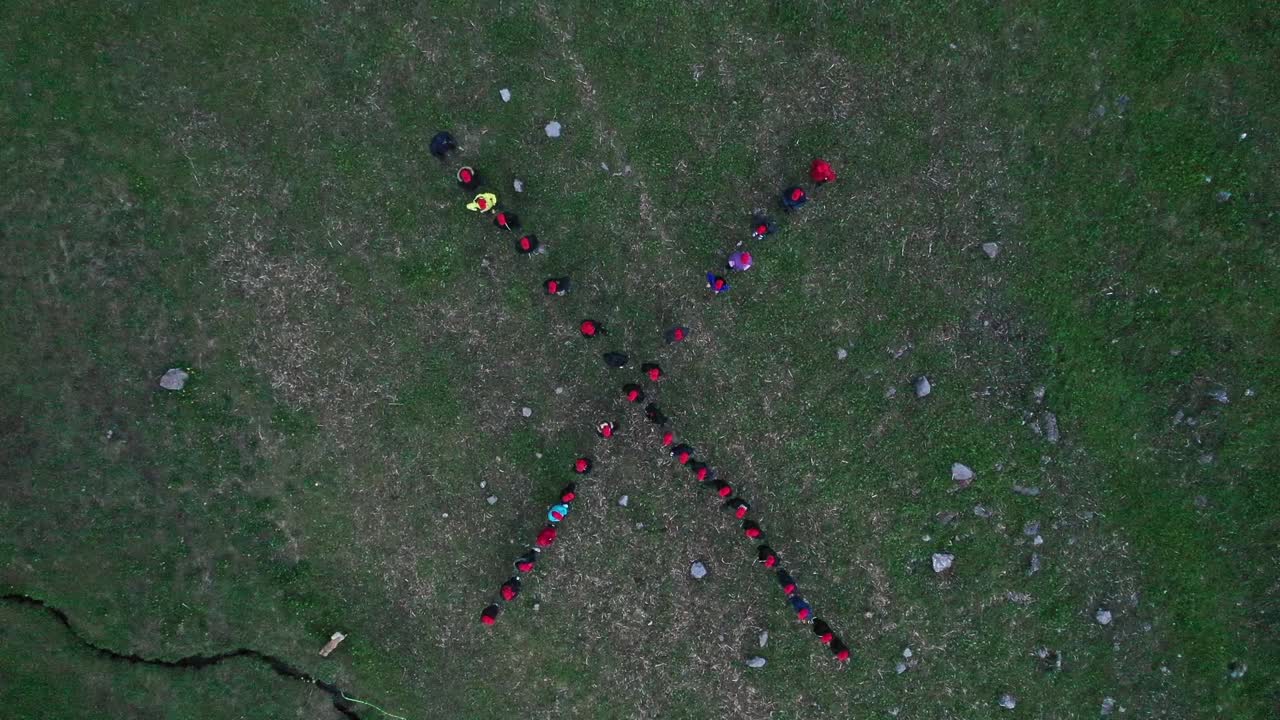 grupo de personas formando la letra x en el campamento con carpas