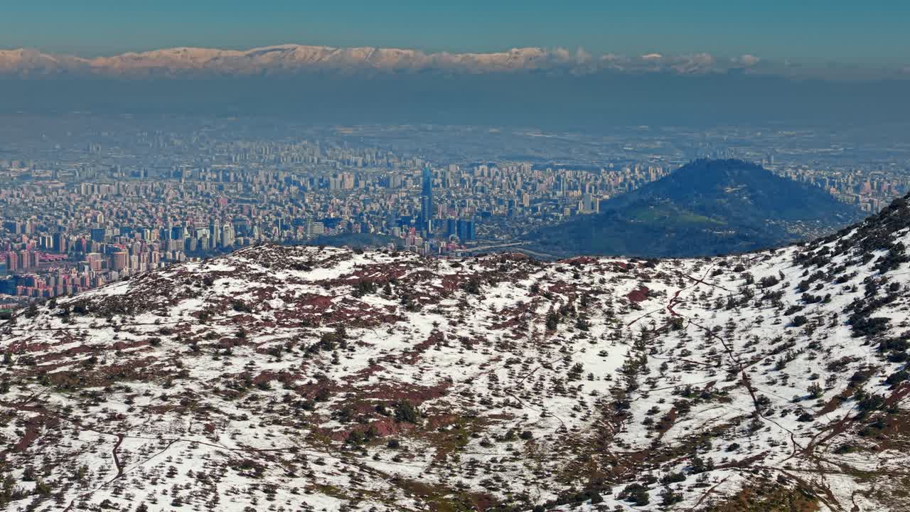 Upward pedestal shot revealing snowy hills in Santiago, Chile, with the skyline visible in the background