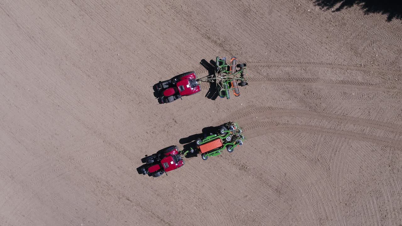 Fixed zenithal drone shot showing tractor unfolding agricultural equipment in Prague on a sunny day