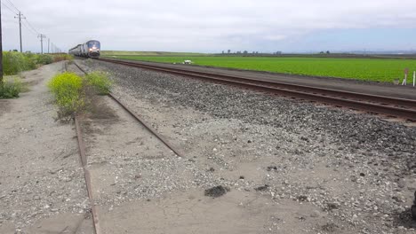 an amtrak train travels at high speed through california farm fields