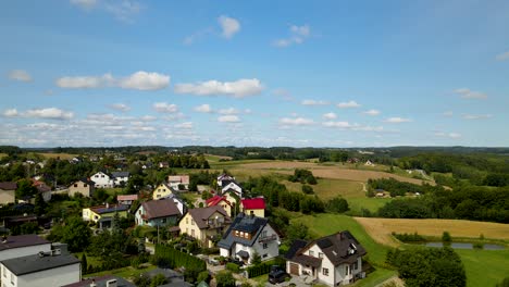 cottage houses on beautiful green meadows surrounded by green forest in brodnica - aerial descending