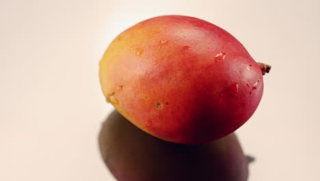 Mango-Rotiert-Auf-Einer-Silbernen-Reflektierenden-Oberfläche-In-Zeitlupe-Und-Glänzt-Und-Schimmert