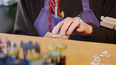 close up of female jeweller working on brooch with saw in studio