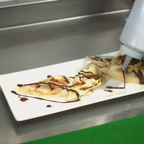 chef is working on the presentation of the dish in a commercial kitchen. pancakes with chocolate sauce on a plate sqare video