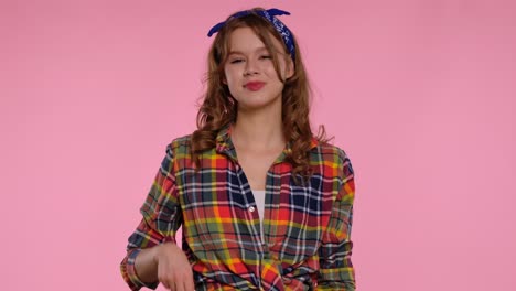 young woman in plaid shirt smiling with pink background a young woman with curly hair and a blue bandana wears a colorful plaid shirt against a pink background smiling confidently