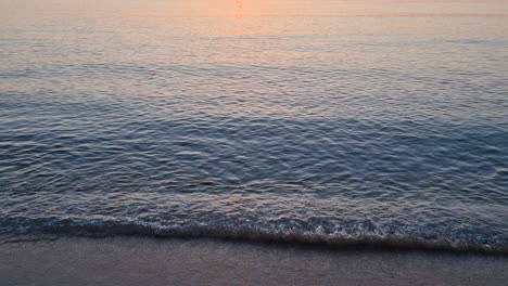 sea waves splashing on sandy beach at sunrise