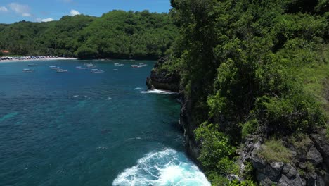 Una-Isla-Solitaria-Frente-A-La-Costa-De-Nusa-Penida-Con-Un-Arco-Rocoso-Y-Vegetación-Con-Olas-Azules,-Aérea