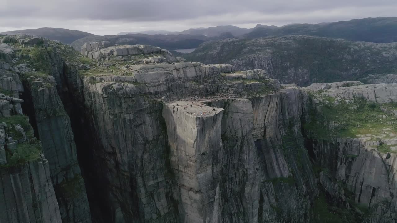 Aerial Slomo flying towards the Preikestolen, Norway, with Tourists on top Walking and Photographing the Scenery