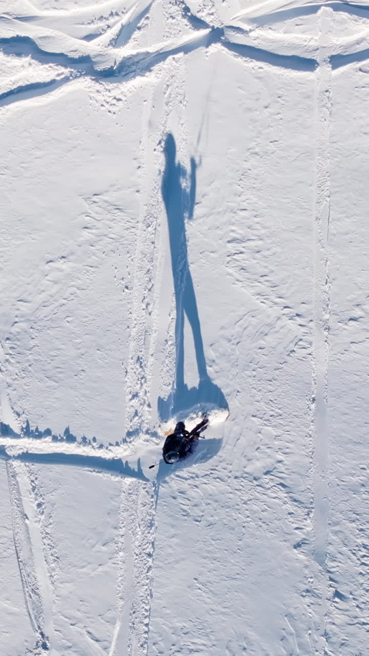 Aerial drone view of a sportsman snowkiting on the Giau Pass in the Dolomites, Italy. Vertical