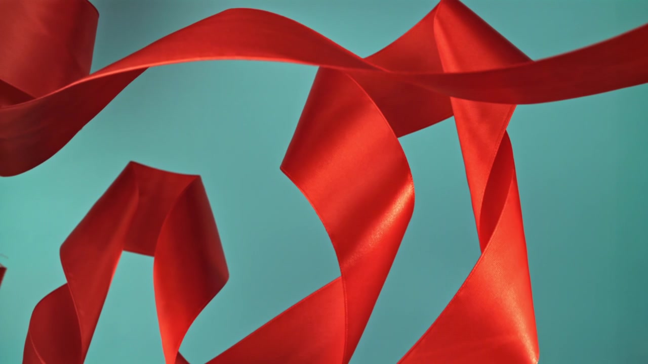Abstraktes rotes Satinband auf türkisfarbenem Hintergrund.