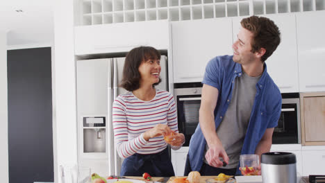 Video-of-diverse-couple-preparing-fruits-for-juice