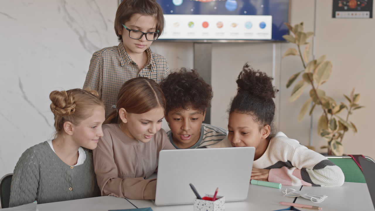 Multiethnic Schoolchildren Having Fun while Studying on Laptop
