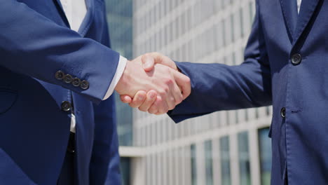 handshake between two suited caucasian business men outdoors, close-up