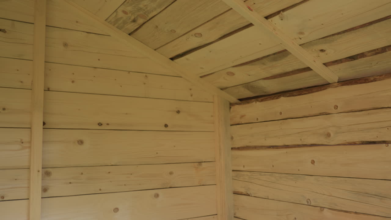 Natural wood ceiling interior of kids toy room with exposed grain, knots, and angled beam structures in warm sunlight, emphasizing natural patterns, organic texture, and handmade carpentry detail