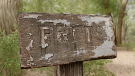 weathered wooden sign with carved text "p&t is" in an outdoor setting