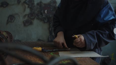 Close-up-of-a-mans-hands-in-a-workshop-cutting-trough-a-piece-of-cardboard