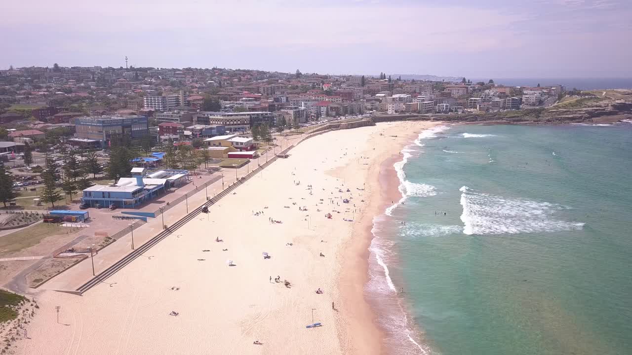 vuelo aéreo inverso sobre la playa de arena en el suburbio oriental del centro de la ciudad de maroubra y el agua azul transparente del océano