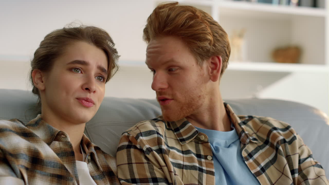 la esposa tomando el control remoto cambiando el canal de televisión de cerca. la pareja descansando en casa.