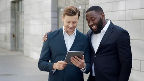 two happy businessmen reading good news on digital tablet in modern city