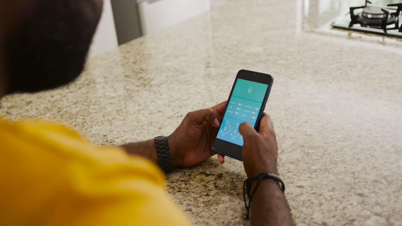 Afrikansk mann i gul skjorte ser på en turkis app, tapper på telefonen ved en spraglete disk og justerer innstillinger.