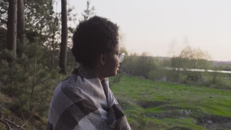 Una-Mujer-Joven-Contemplando-La-Puesta-De-Sol-En-El-Bosque-Cubierta-Por-Una-Manta-1