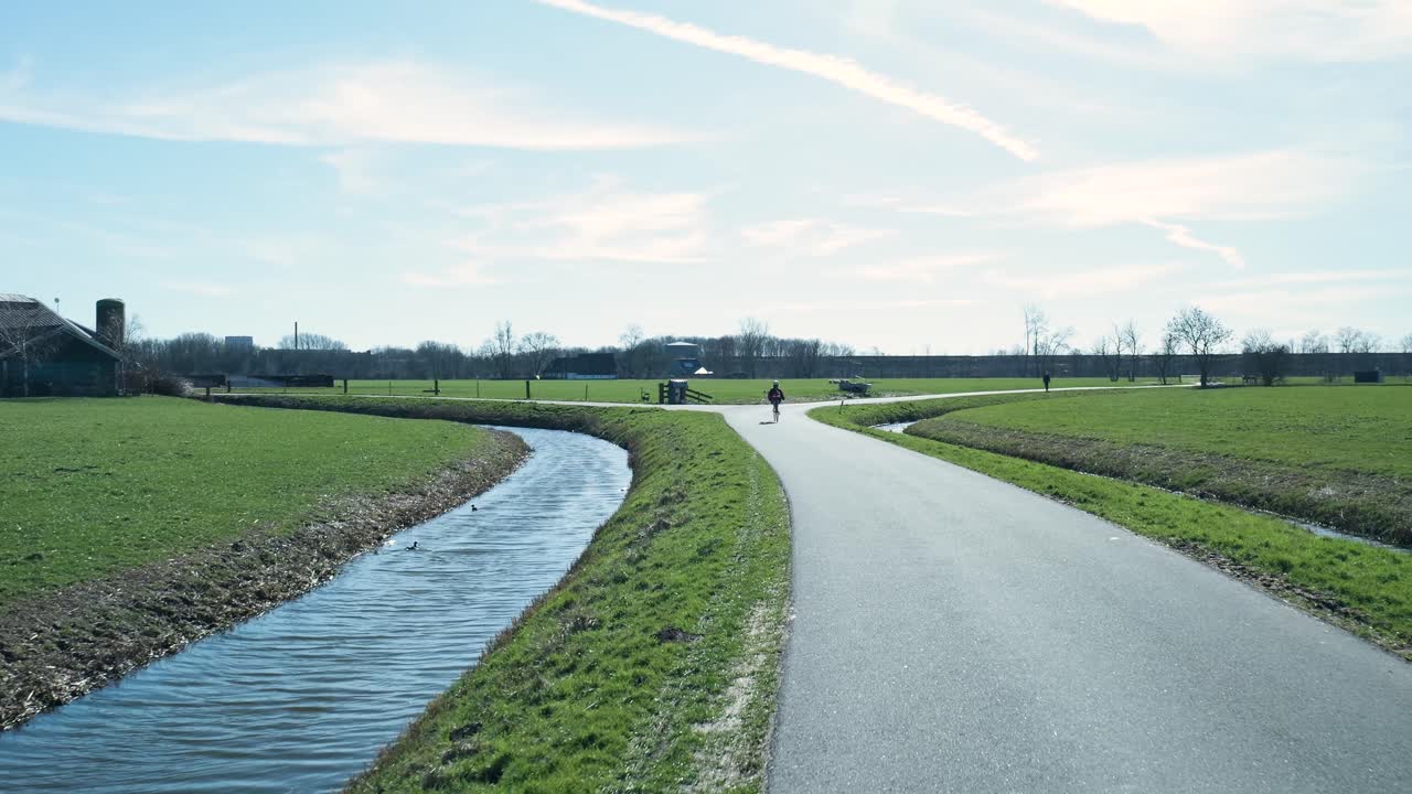 Fietser op een geplaveid pad door groene velden