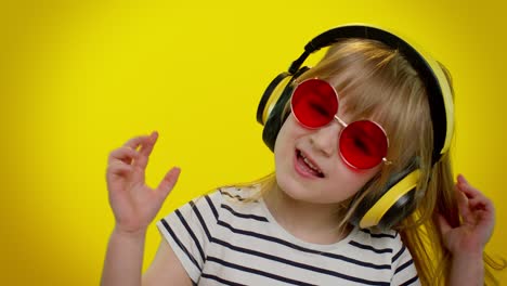 Playful-funny-little-kid-child-girl-listening-music-via-headphones,-dancing-disco-fooling-having-fun