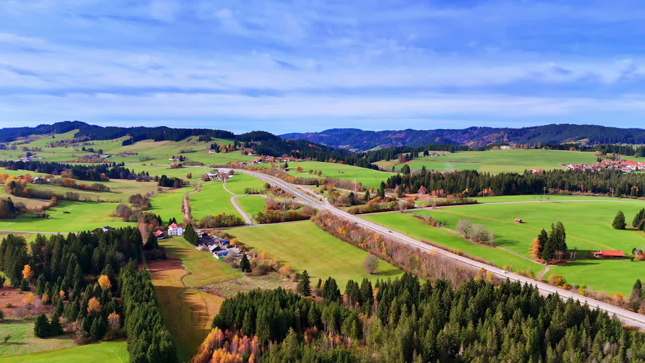 Wide view of autumn fields and hills. Expansive autumn landscape with bright fields, winding roads and forested hills