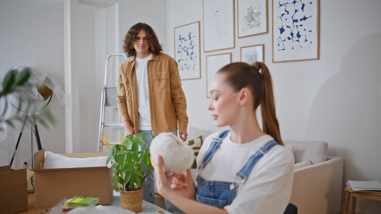 Property owners unpacking boxes arranging decor items in new home closeup