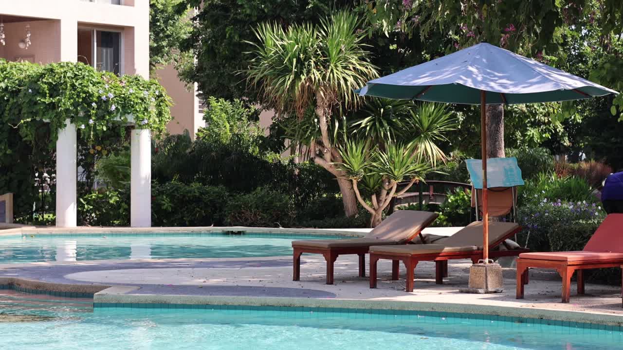 Person cleaning poolside area at a resort