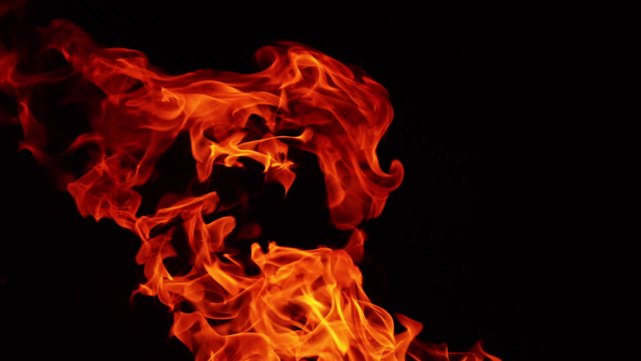 Dangerous flames of red hot fire rising into the air. Close up view of blaze in the darkness.