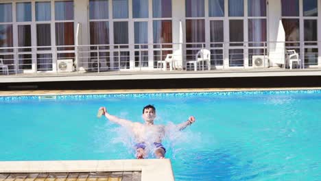 un joven atlético con pantalones cortos de natación cayendo a la piscina.