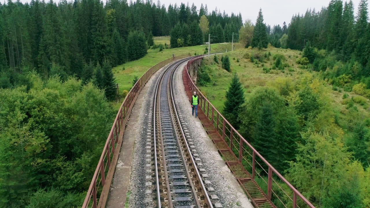 trabajador en un puente de viaducto ferroviario con vistas al bosque