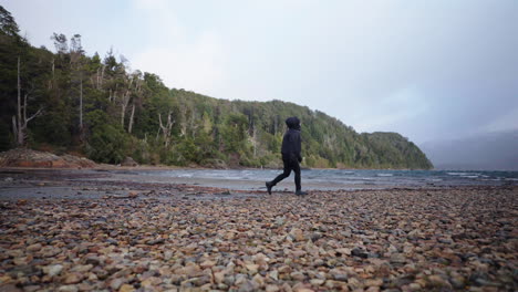 frustrated person releasing tension on a rocky beach surrounded by forested area