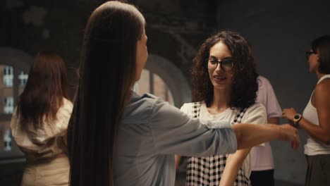 A-girl-with-curly-hair-with-glasses-communicates-with-a-girl-with-straight-long-hair-in-group-therapy-and-they-hug.-Achieving-mutual-understanding-and-pleasant-communication-in-group-therapy