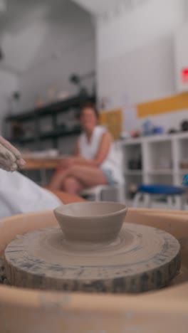 close-up of hands shaping clay on a pottery wheel in a creative workshop
