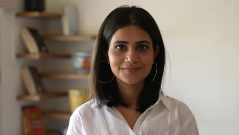 smiling asian young woman in formal outfit looking to camera inside at home.