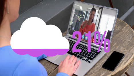 Animation-of-cloud-upload-icon-against-rear-view-of-woman-having-a-video-call-on-laptop-at-a-cafe