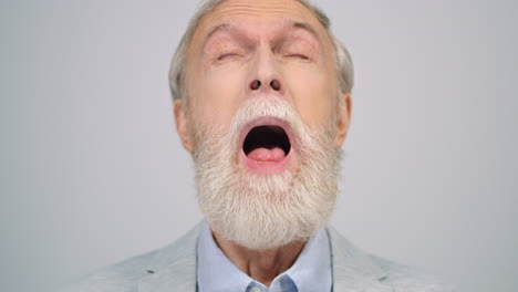 happy old man smiling to camera indoor. cheerful guy wiping face in studio.