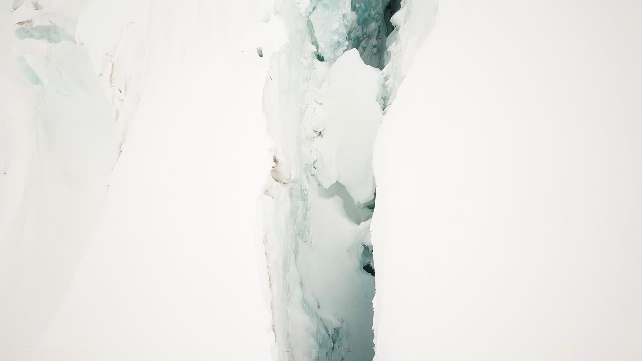 Snowy Swiss glacier split by a deep crevice, aerial view of Jungfraujoch area