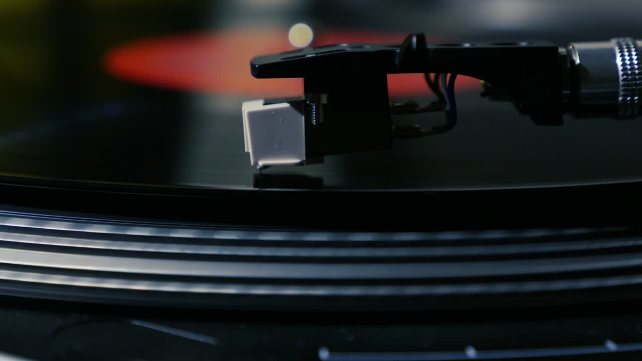A needle is put down on the spinning black vinyl on the turntable slow motion