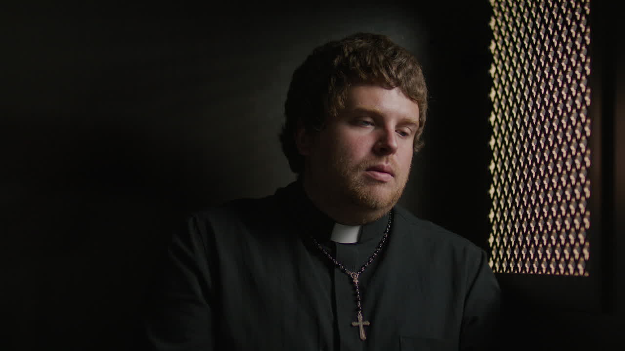Priest Responding to Penitent through Ornate Screen in Confessional Booth