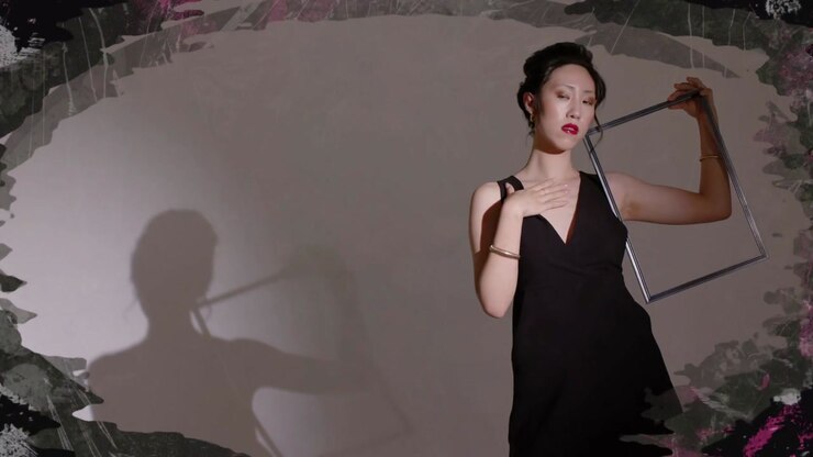 Female model raising frame, rotating it to frame face and creating shadow interplay for fashion