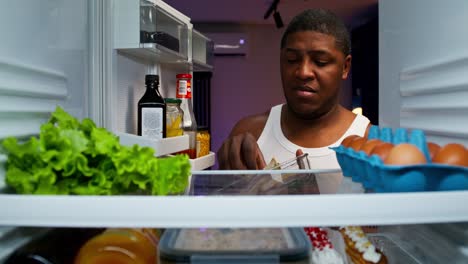 hombre comiendo sándwich del refrigerador por la noche